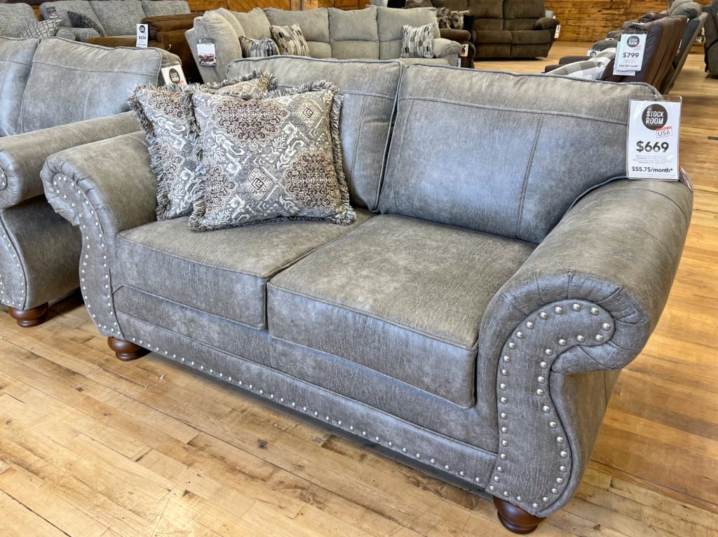 traditional lodge style sofa with nailhead trim in leather-look beige