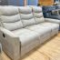 Manual reclining sofa in a light beige suede-look fabric in The Stock Room discount furniture warehouse at Benson Stone Co in Rockford, IL