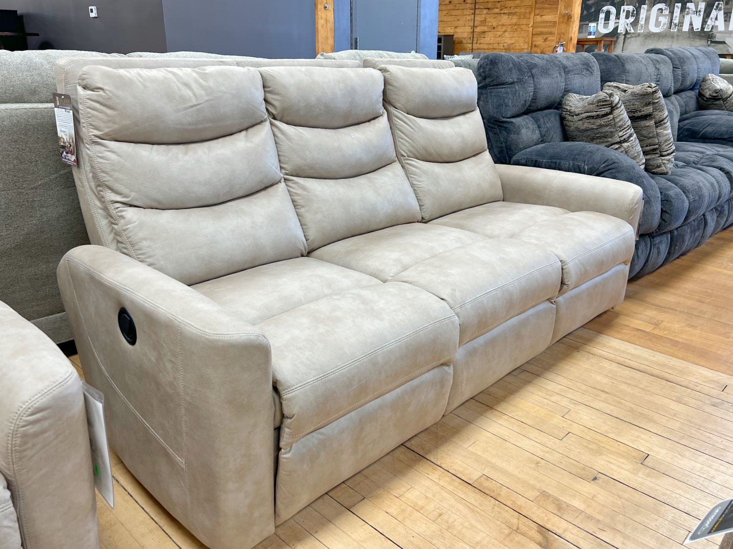 Manual reclining sofa in a light beige suede-look fabric in The Stock Room discount furniture warehouse at Benson Stone Co in Rockford, IL