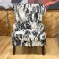 High-back wingback accent chair with a bold, abstract black and white textured pattern, including a matching throw pillow, displayed on a light wood floor at a furniture store.