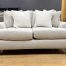 A contemporary light beige upholstered loveseat decorated with textured white and tan accent pillows.
