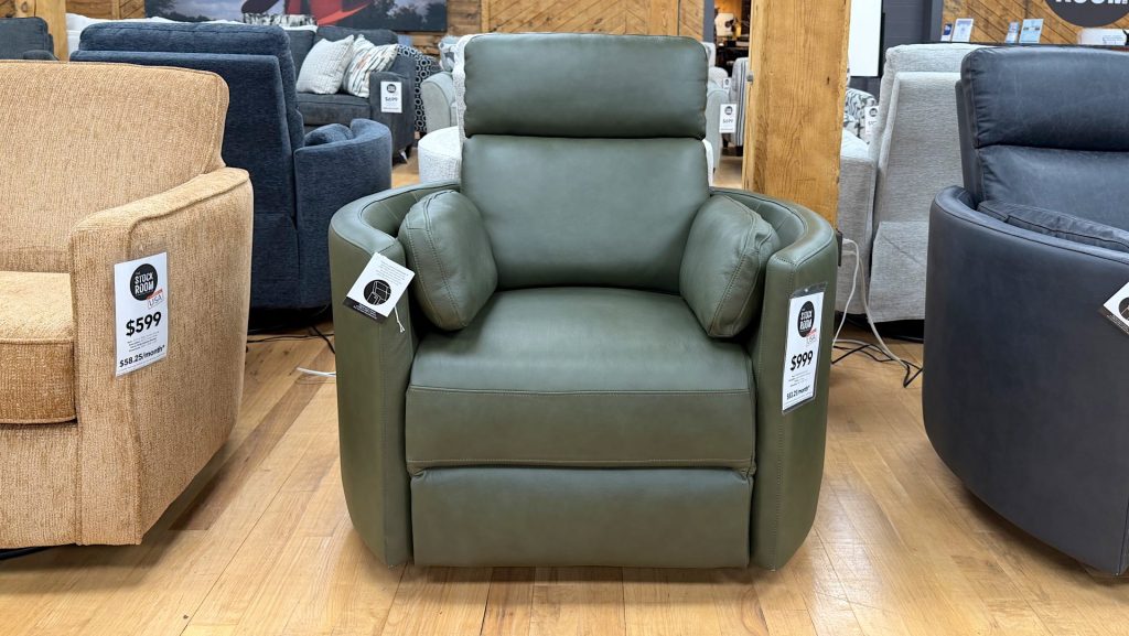 Modern olive green leather recliner chair with integrated side bolster pillows displayed on a light hardwood floor at The Stock Room showroom.