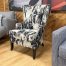 A modern wingback armchair with an abstract black and white pattern and dark wood legs.