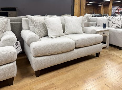 Tezza-9518 A contemporary light beige upholstered loveseat decorated with textured white and tan accent pillows.