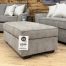 A contemporary oversized upholstered ottoman in a neutral taupe-grey fabric.